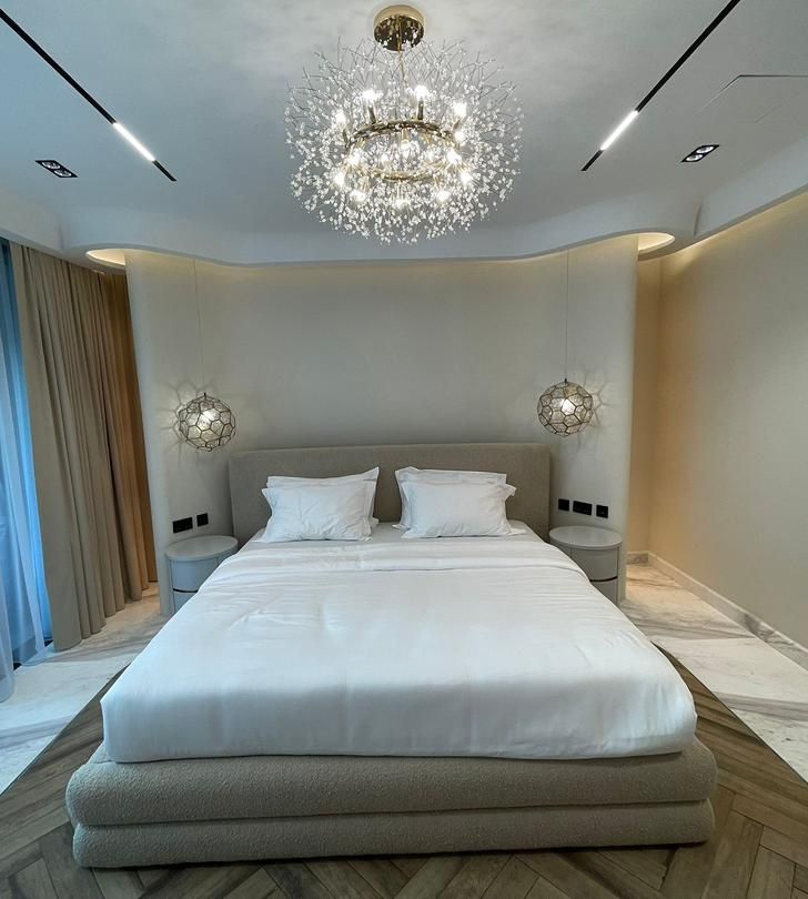 Softly lit bedroom designed by Maya Luxe Homes, crystal pendant lighting over a neutral bed